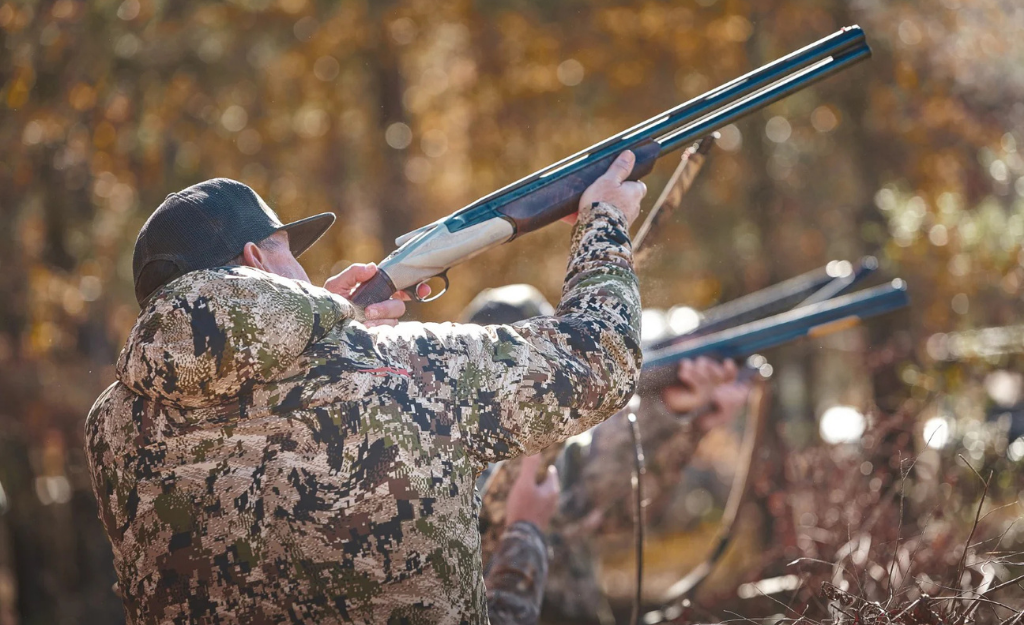 two hunters in Alabama take aim with shotguns dressed in mossy oak camo hoodies