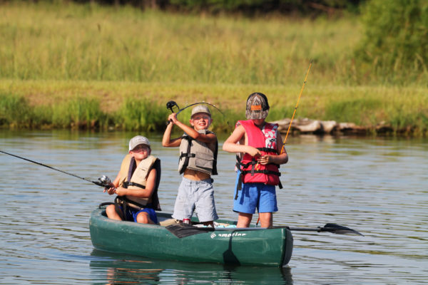 3 kids fish in a canoe at Soggy Bottom Lodge