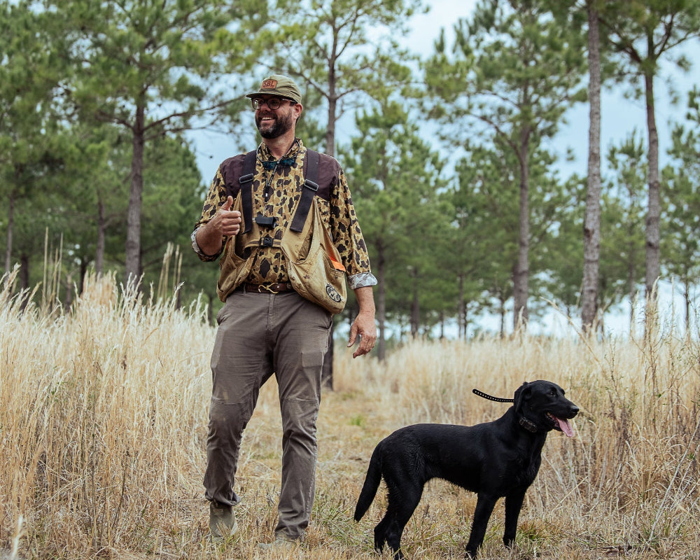 Man walking with a black dog in a forested area