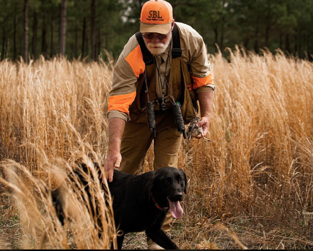 Man in hunting gear with a dog in a field